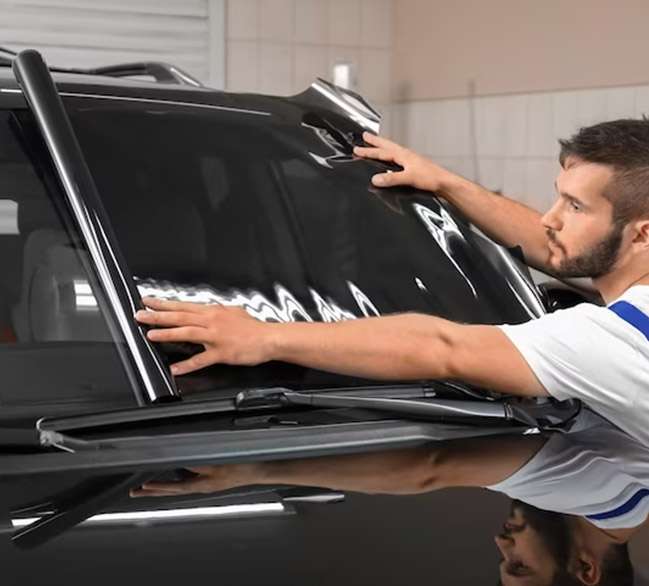 man applying car window tint