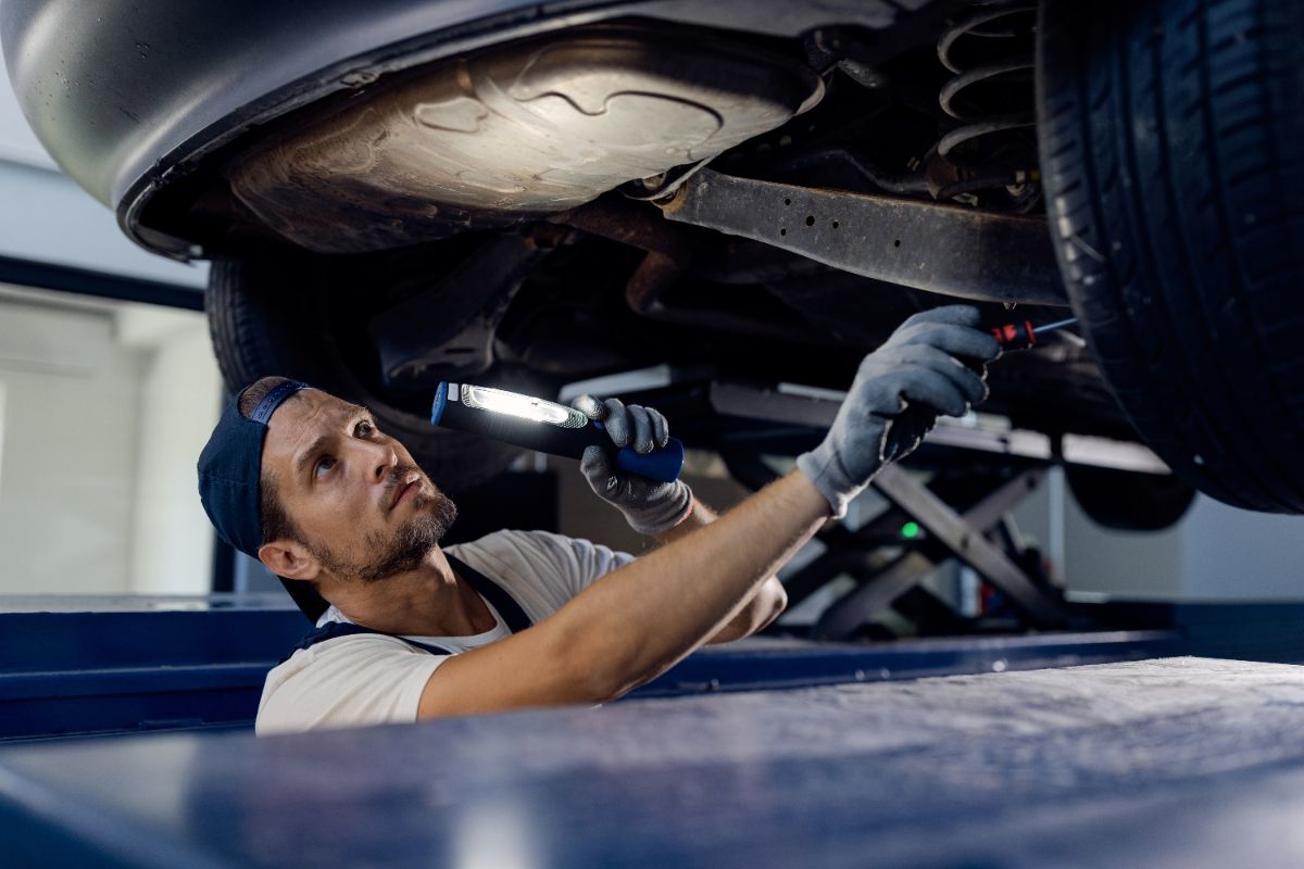 Technician inspecting a car underbody